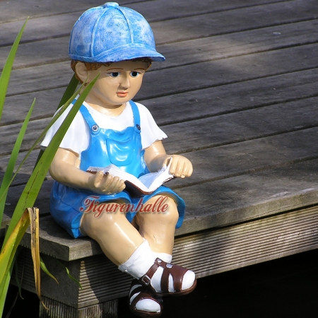 Junge sitzend mit Latzhose